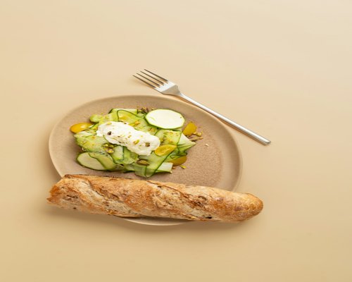 A freshly prepared salad inside a ceramic plate alongside rye bread slices